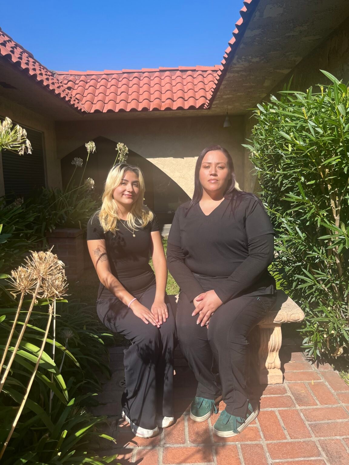 portrait style image of two dental assistants from Newsham Dental posing outside of the building