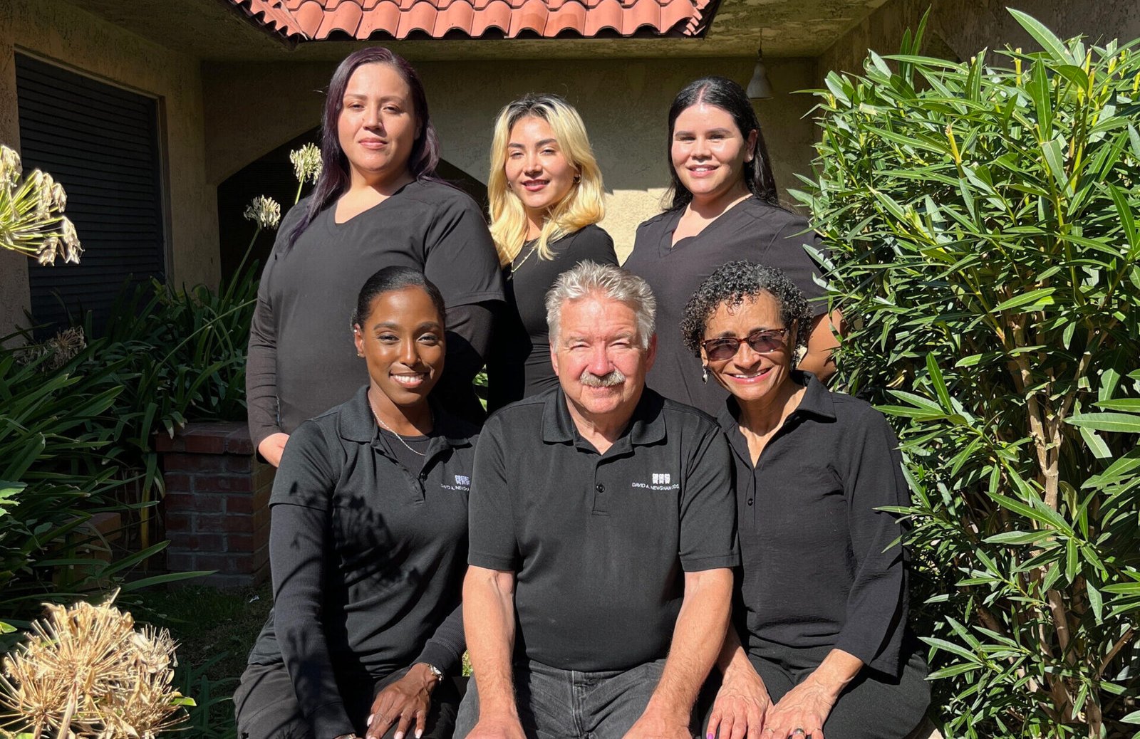 Dental team from Newsham Dental in Rialto, featuring Dr. David Newsham, smiling in a welcoming outdoor setting, showcasing a family-friendly atmosphere.