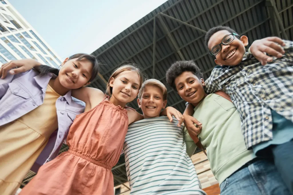 5 children in a group hurdling over the camera smiling for a portrait