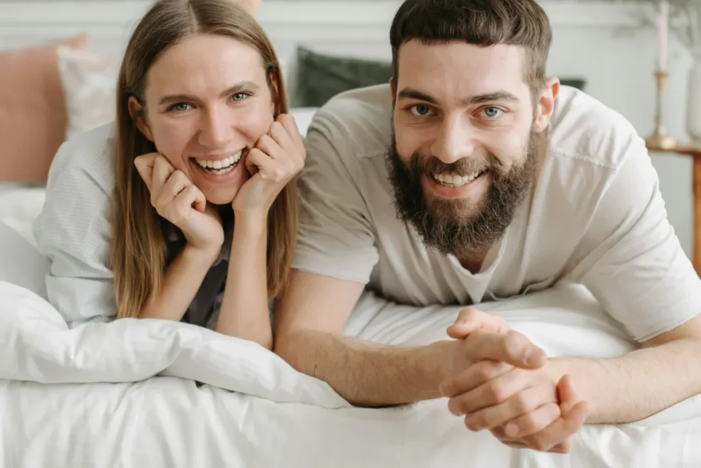 couple on bed smiling at camera showing their smiles