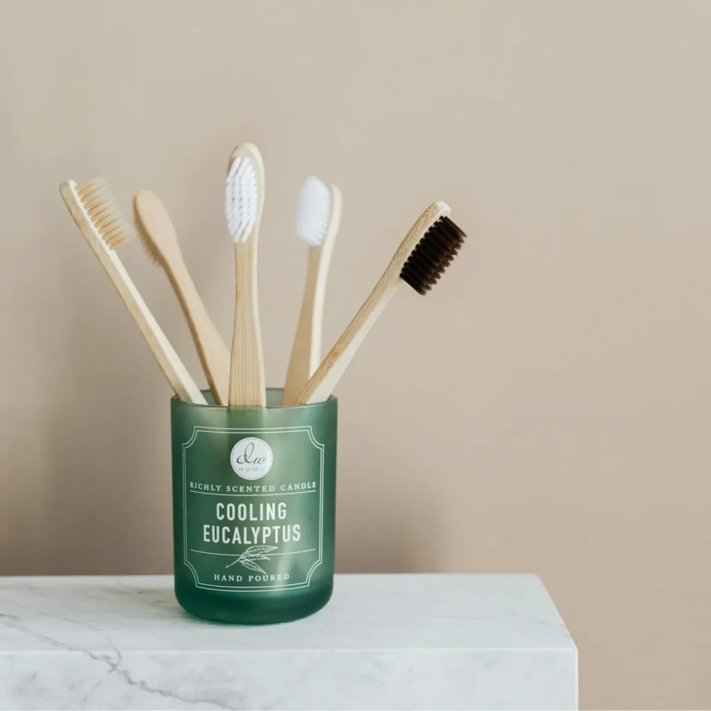aesthetic image of 5 bamboo toothbrushes in a green mason jar on a marble counter