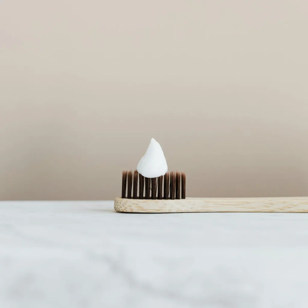 bamboo toothbrush on marble counter with a drop of toothpaste on it