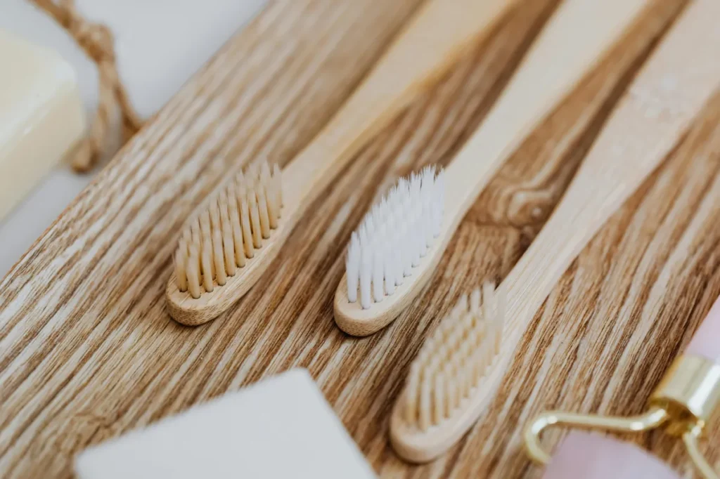 aesthetic image of 3 bamboo toothbrushes on a wooden counter