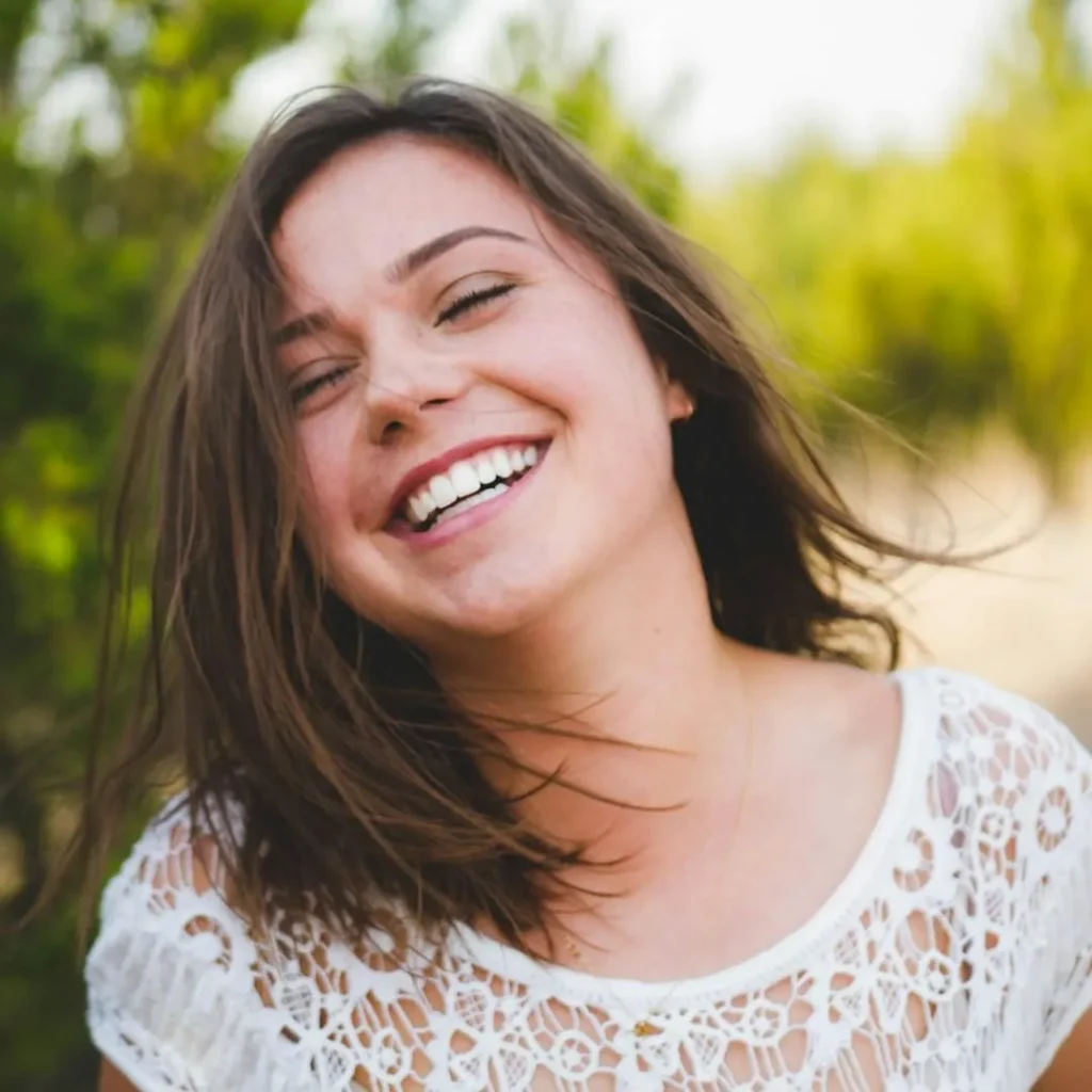 Woman smiling with perfect teeth outside in a green meadow