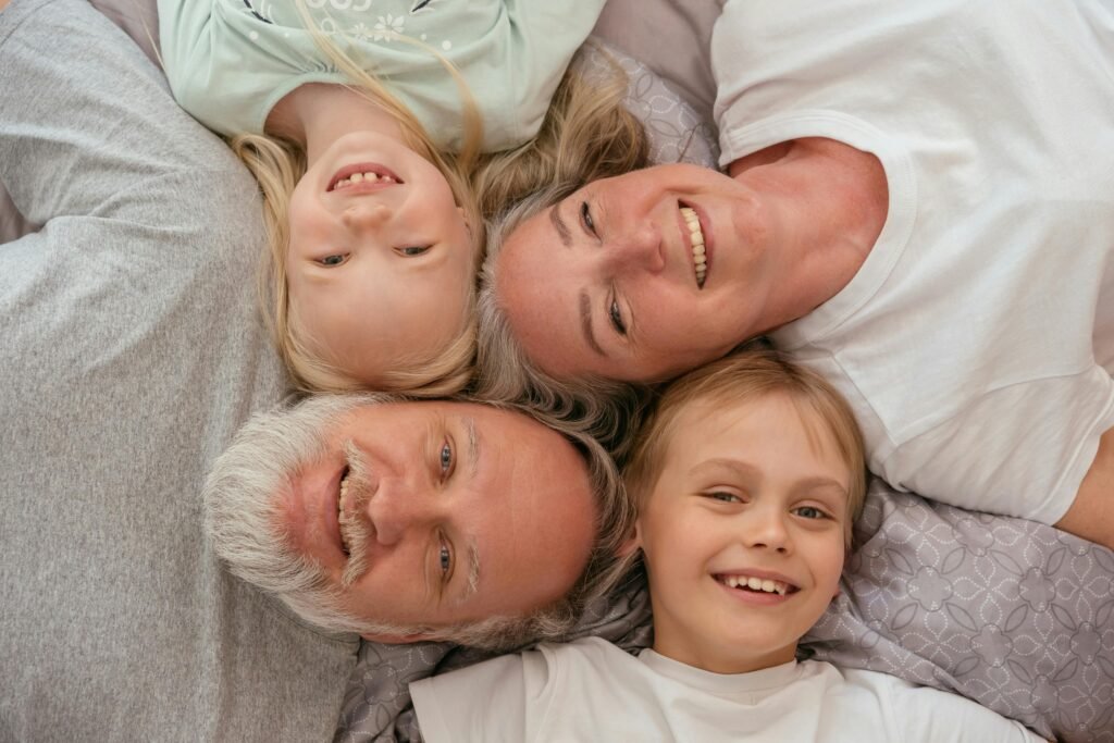 family of 4 laying down on the floor all smiling up at the camera with their heads together